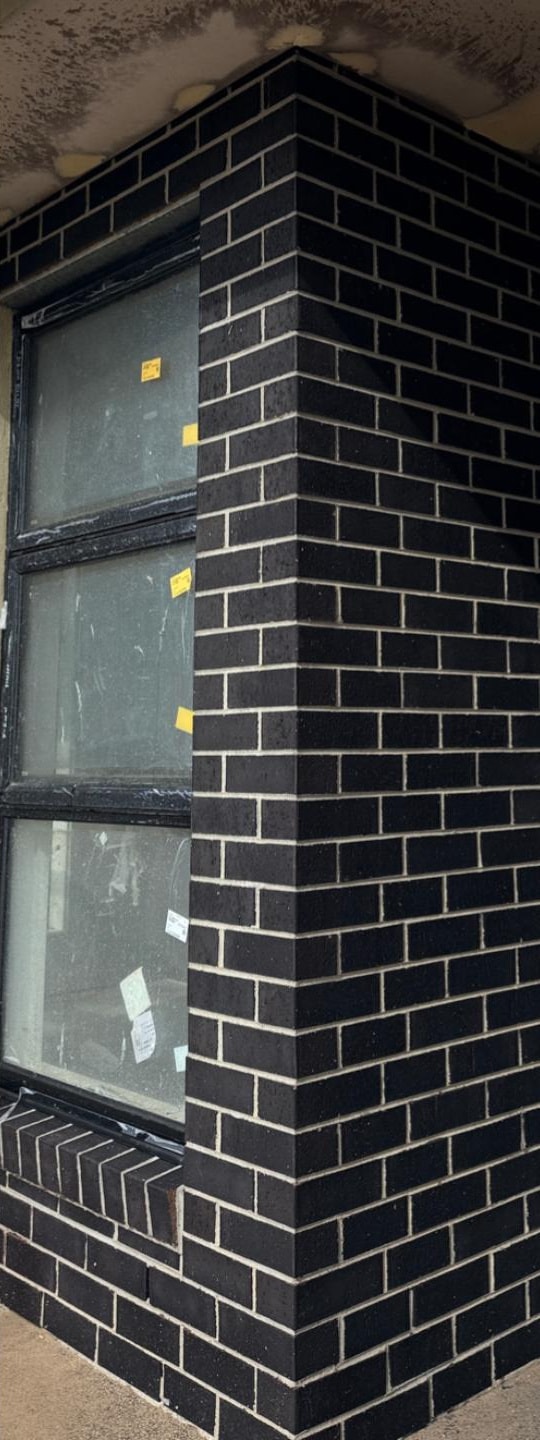 The same black brick window return after cleaning, with clean face brick and intact pale joints