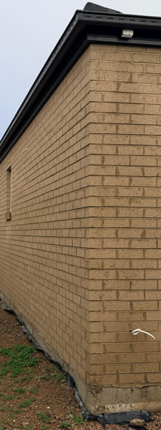 Buff brick wall before cleaning, with run marks and streaking down the face brick
