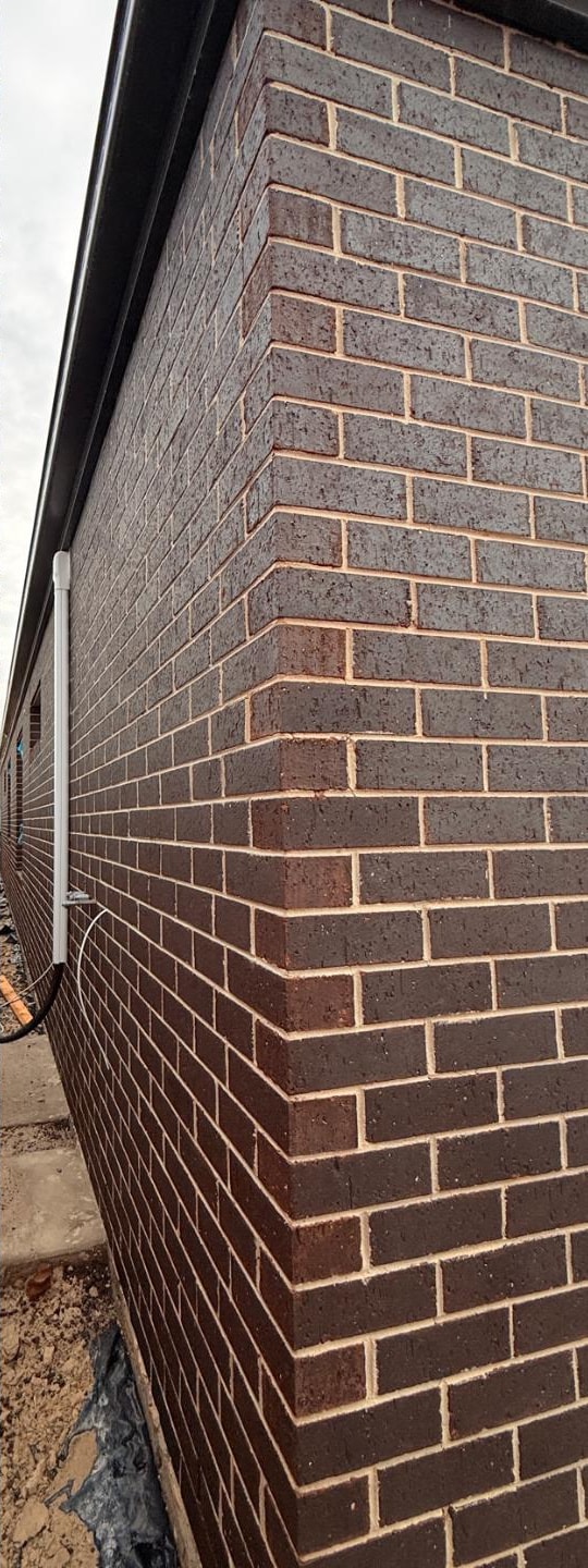 The same charcoal brick corner after brick cleaning, with the brown-red brick colour restored