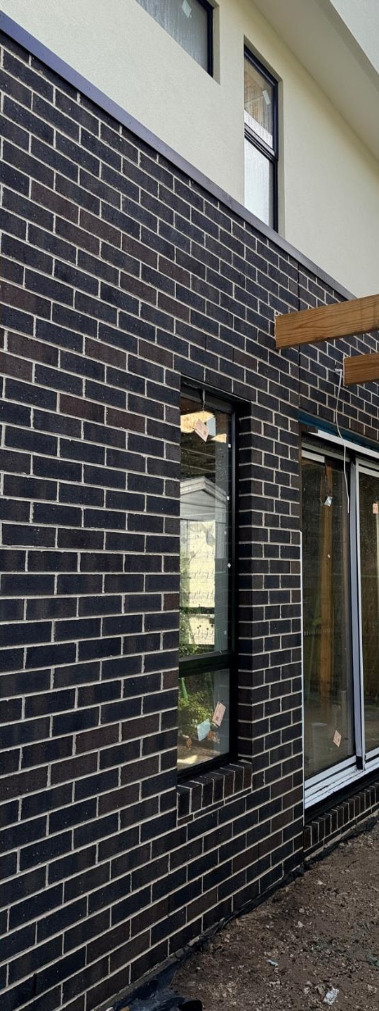 The same dark brick elevation after cleaning, with clean face brick and undamaged window frames