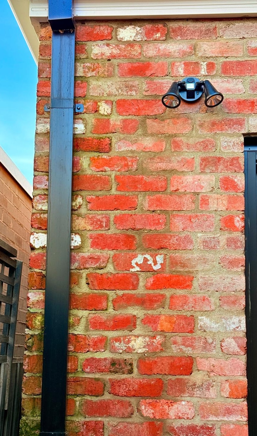 Red brick house wall before cleaning, dulled by algae growth with paint and render splash on the brickwork